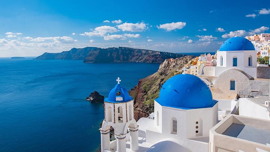 A view of whitewashed buildings with blue-domed roofs in Santorini.