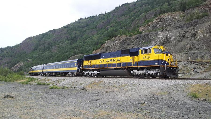 A train passing through mountainous terrain on the Alaska Railroad on the way to Fairbanks in the Summertime.
