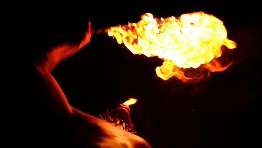 An artistic photo of a traditional Polynesian dancer blowing flames at a Luau in Maui.
